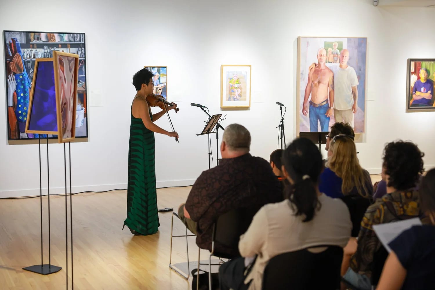 A violinist performing live in the gallery at Capitol Modern, audience seated among the paintings